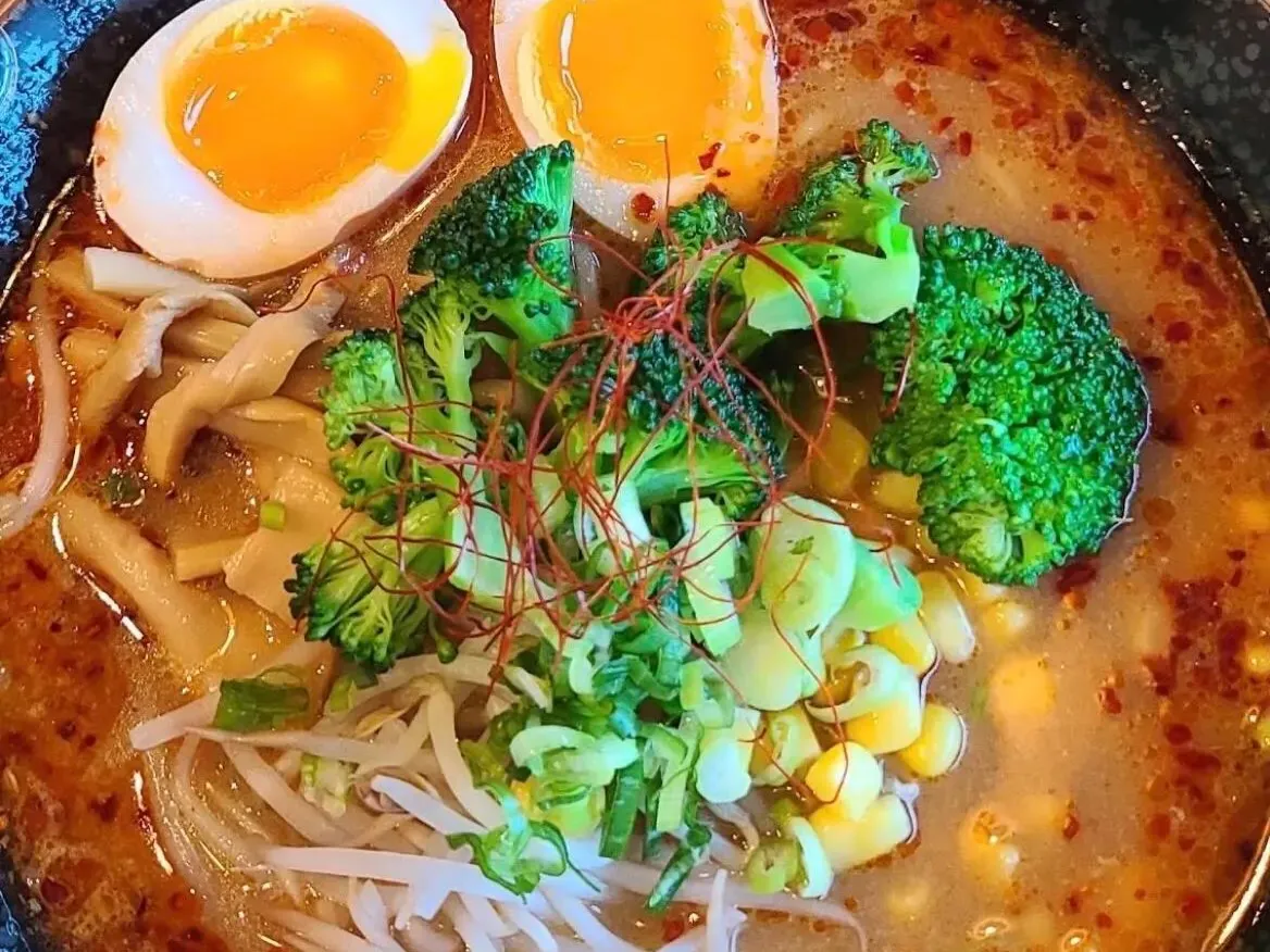 Spicy ramen bowl with soft boiled eggs, broccoli, bean sprouts and corn in rich broth