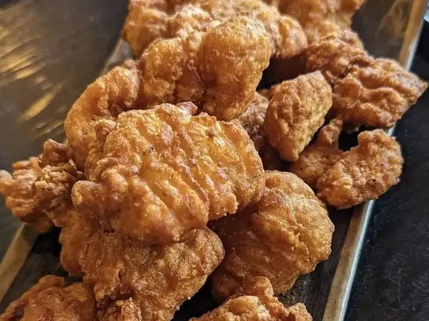 Golden crispy fried chicken pieces with textured crunchy batter on metal tray