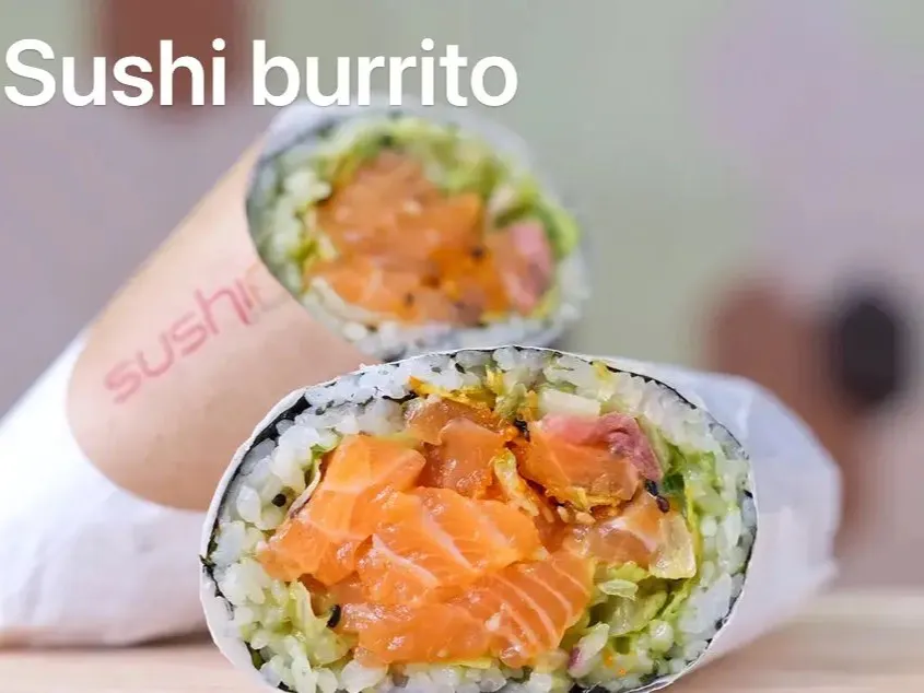 Sushi burrito cut in half, filled with fresh salmon, rice and vegetable fillings