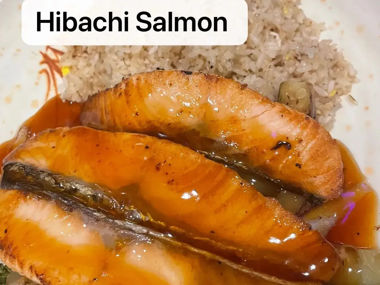 Grilled hibachi salmon fillets with teriyaki sauce and fried rice on white plate